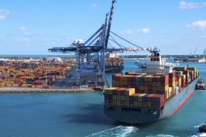 Port of Freeport Bahamas Container shipyard with heavy lifting Cranes and a ship coming in to dock assisted by tug boats